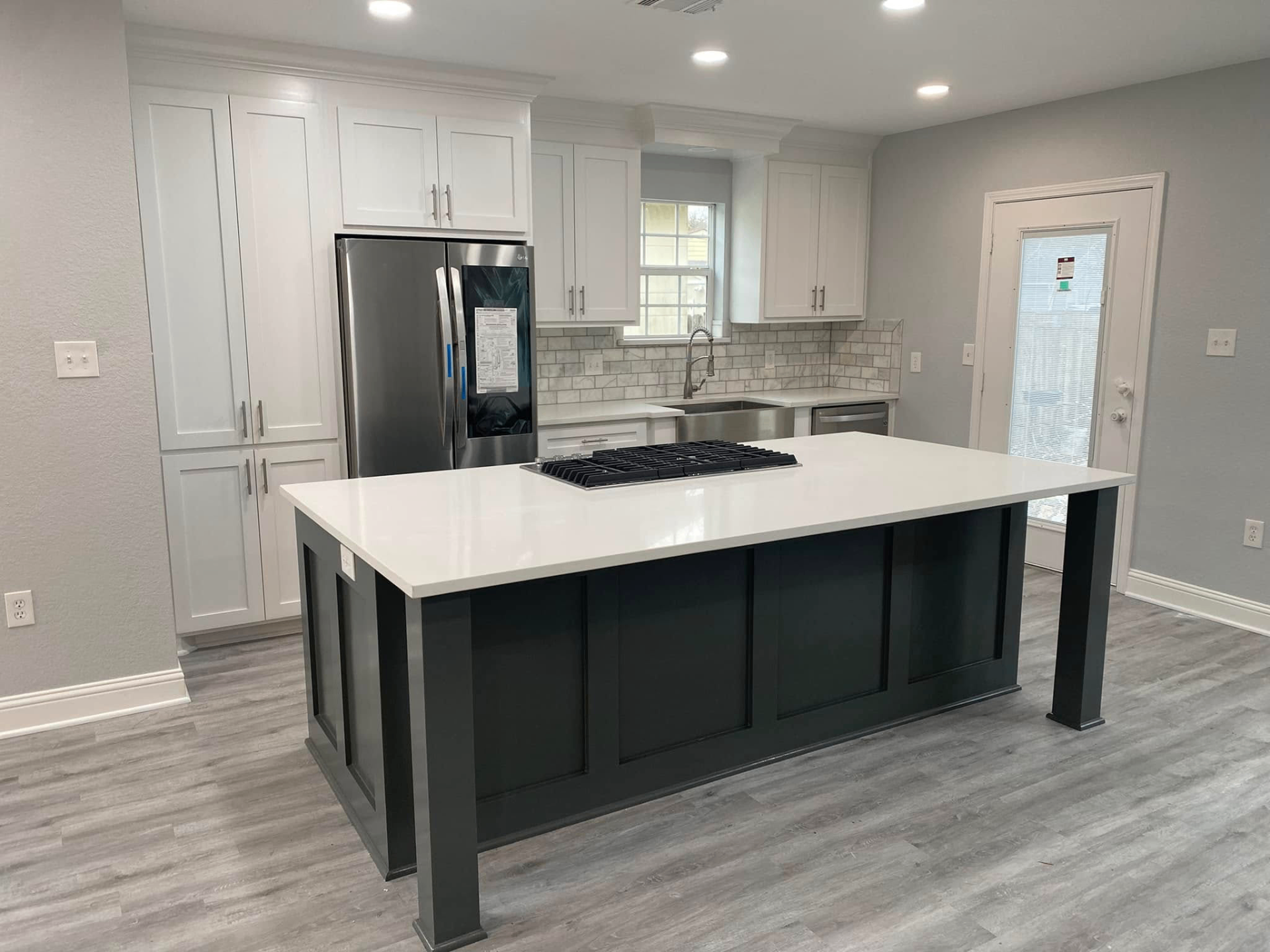 White shaker kitchen with dark green island Open-concept kitchen with white shaker cabinets, dark green island, and quartz waterfall countertop in Sugar Land TX