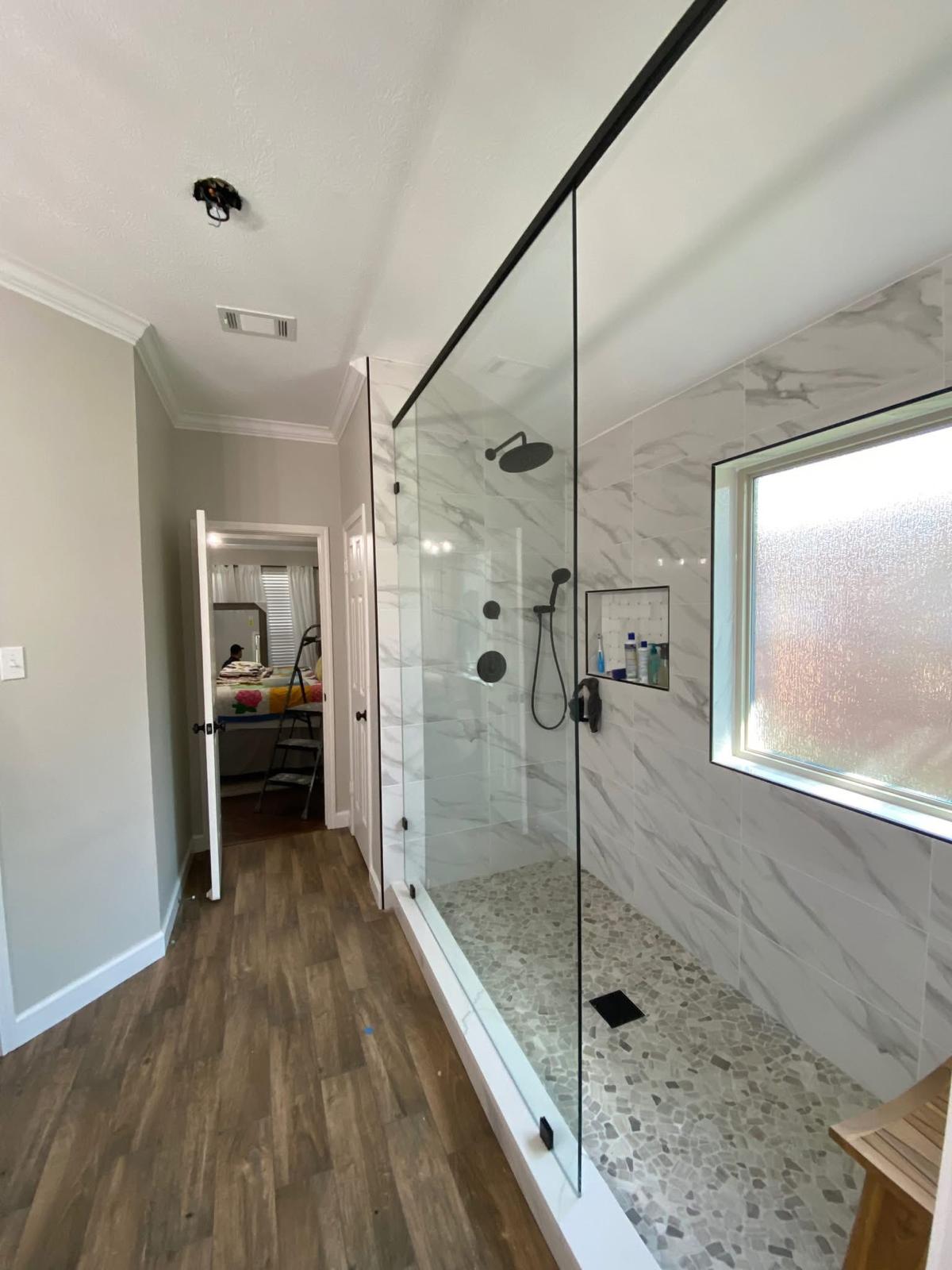 Spa-style shower with rainfall head and bench Spa-style walk-in shower with rainfall head, built-in bench, and black fixtures in Richmond TX