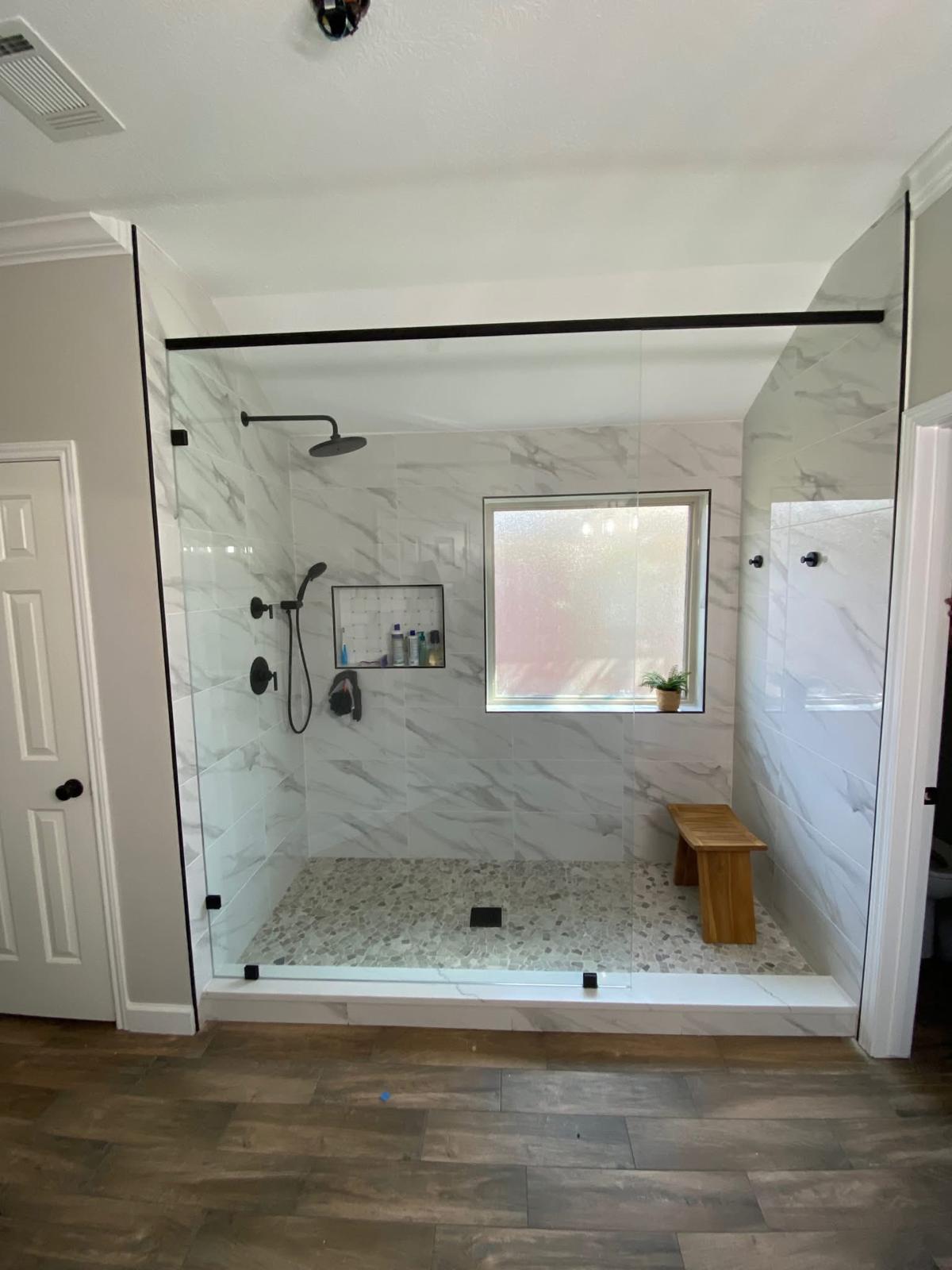 Frameless glass walk-in shower with pebble floor Large walk-in shower with frameless glass door and pebble tile floor in a Sugar Land TX home