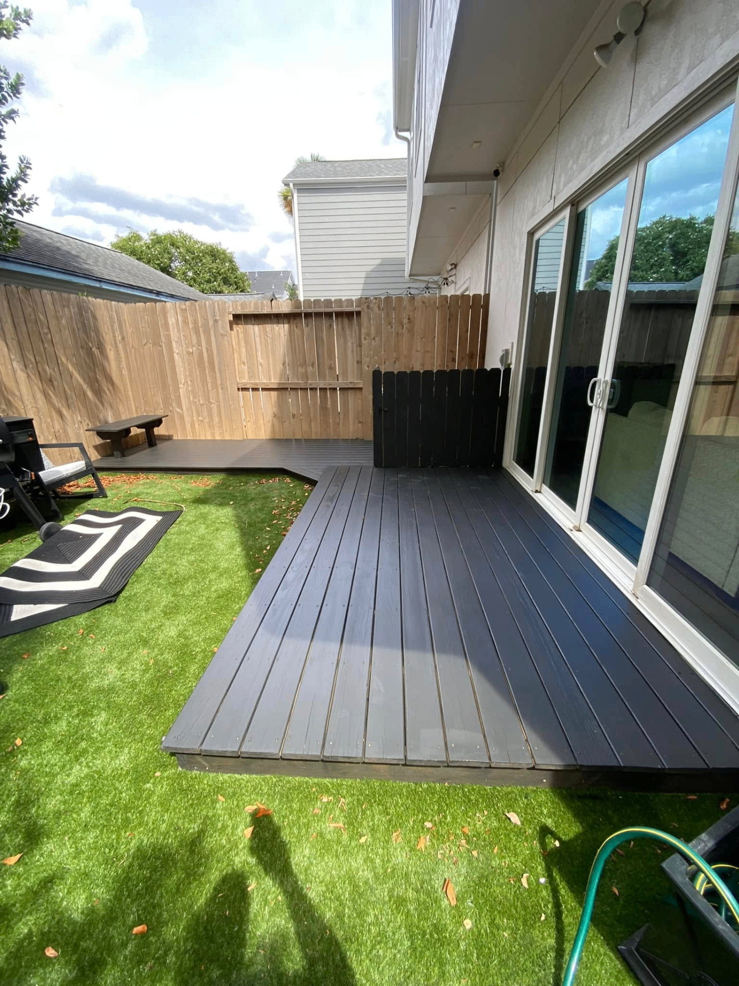 Composite deck with turf and privacy gate Backyard composite deck with artificial turf and privacy fence in a Katy TX outdoor living remodel