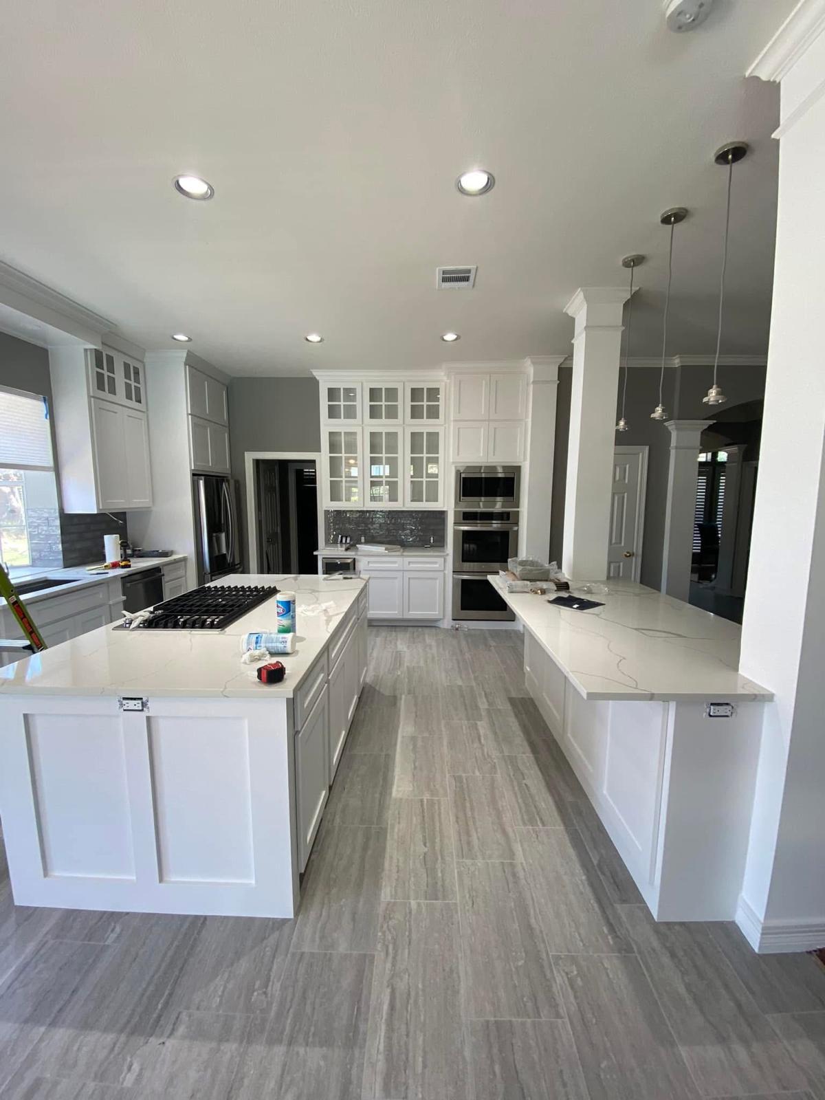 Open-concept chef's kitchen with double island Large open-concept kitchen with white cabinetry and a massive center island in Fulshear TX