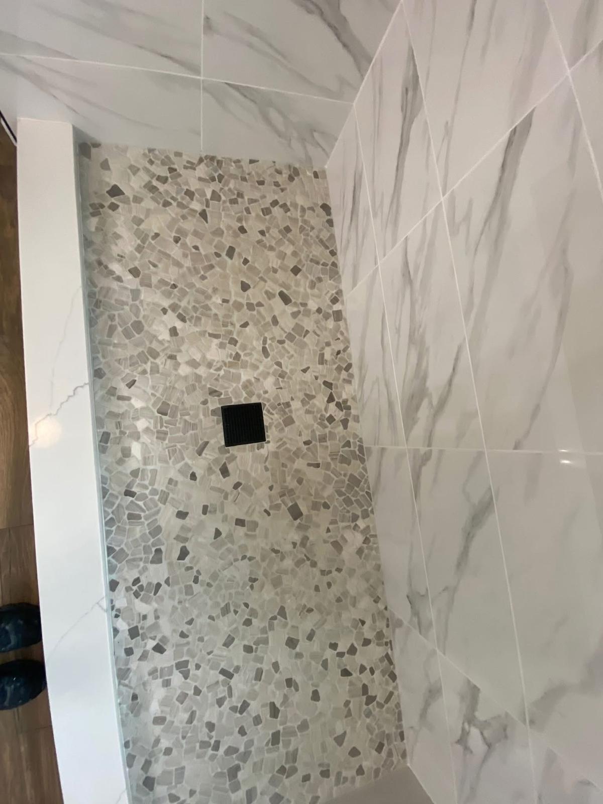 Custom pebble mosaic shower base Custom pebble mosaic shower floor detail in a Fulshear TX bathroom renovation