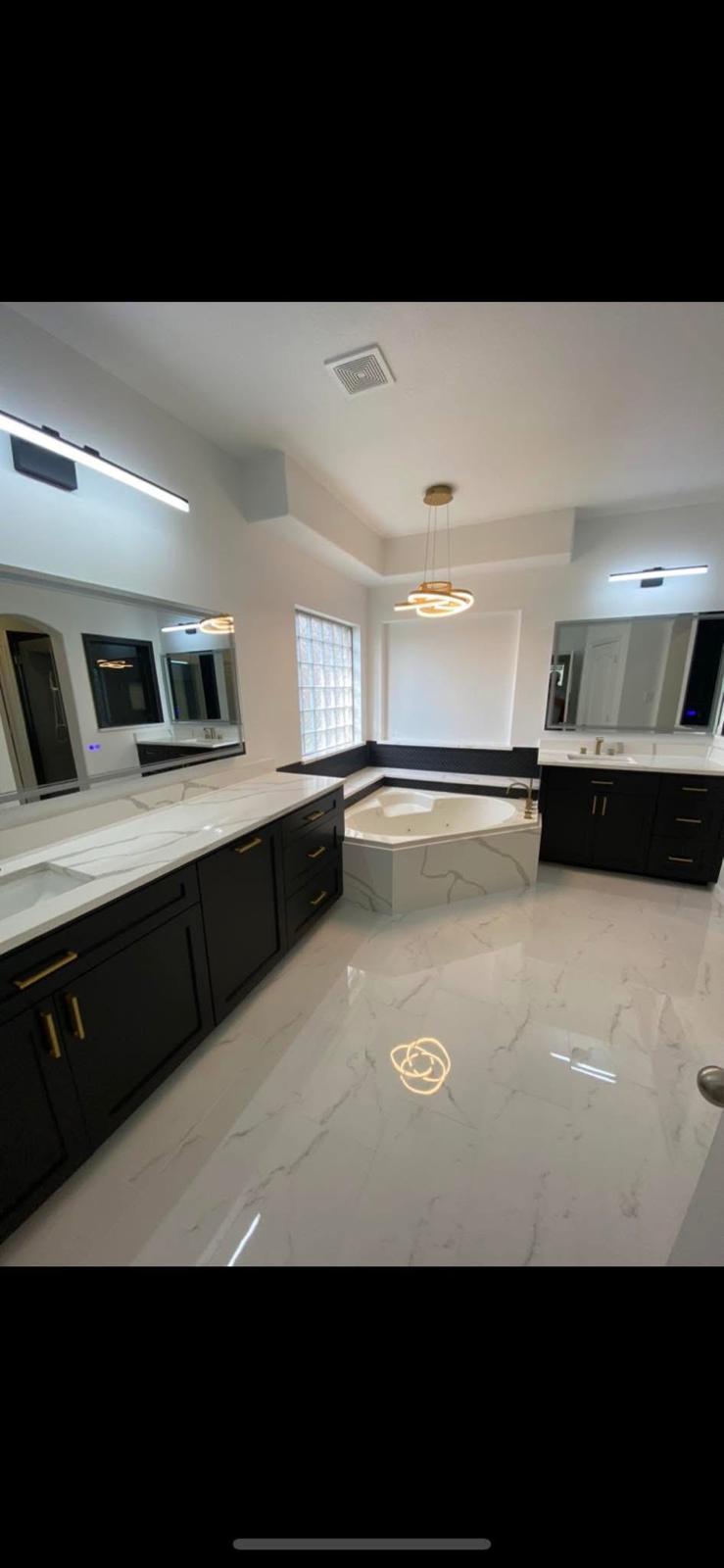 Black and white master bath with chandelier Luxury master bathroom with black cabinets, marble floors, and chandelier in Katy TX