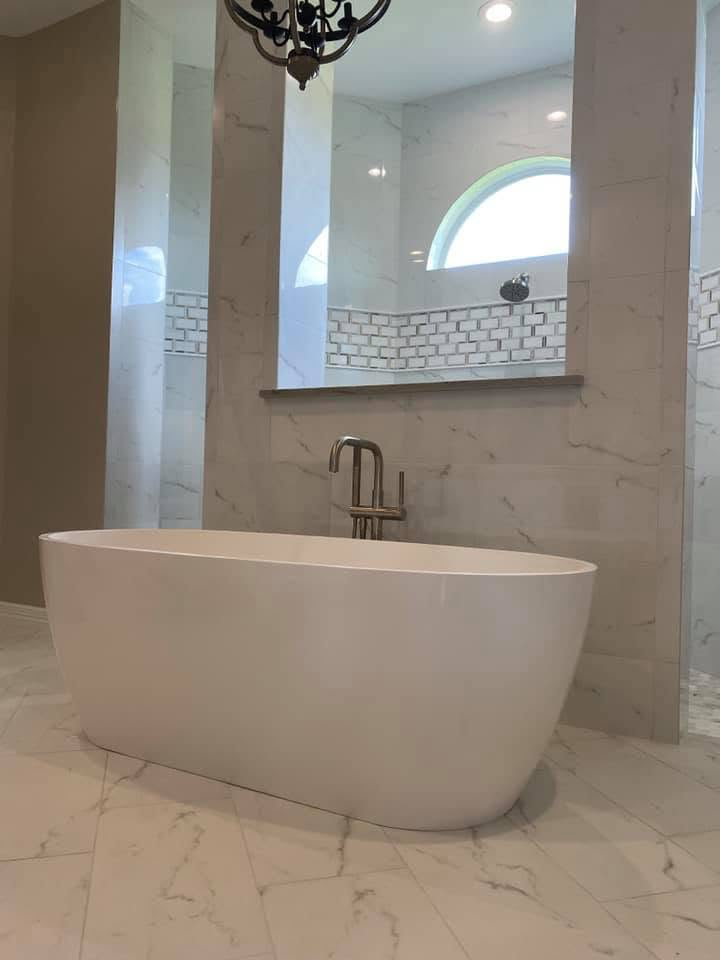 Freestanding tub in marble master bath Freestanding soaking tub with marble surround and chandelier in a Sugar Land TX master bathroom remodel